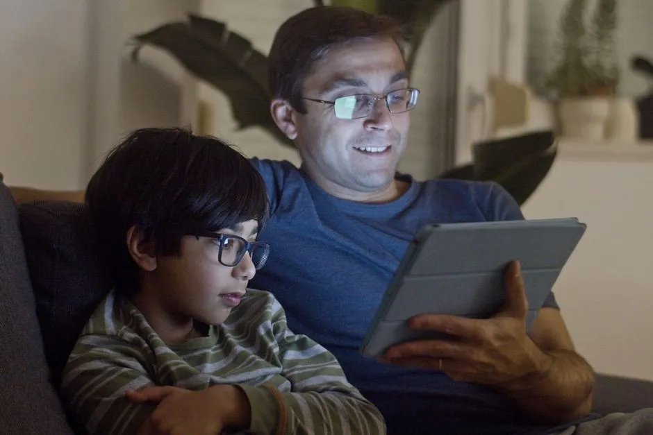 Illustrative photo of a parent and child watching a video together